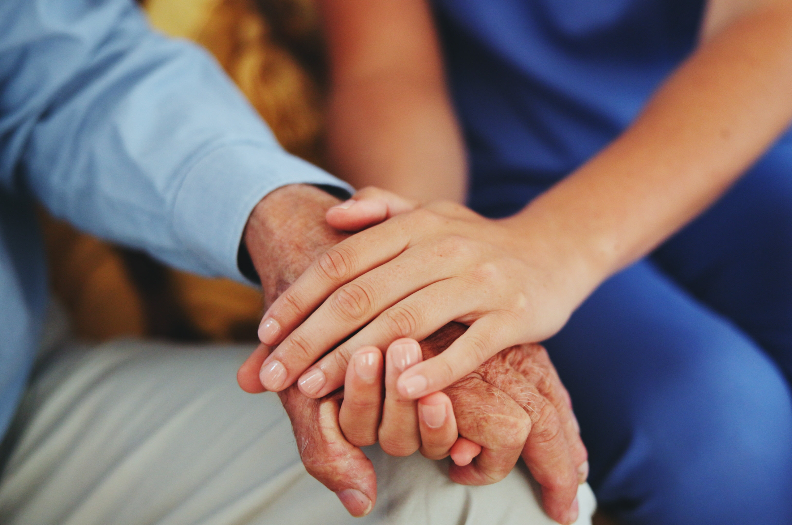 A caregiver holding a senior's hand.