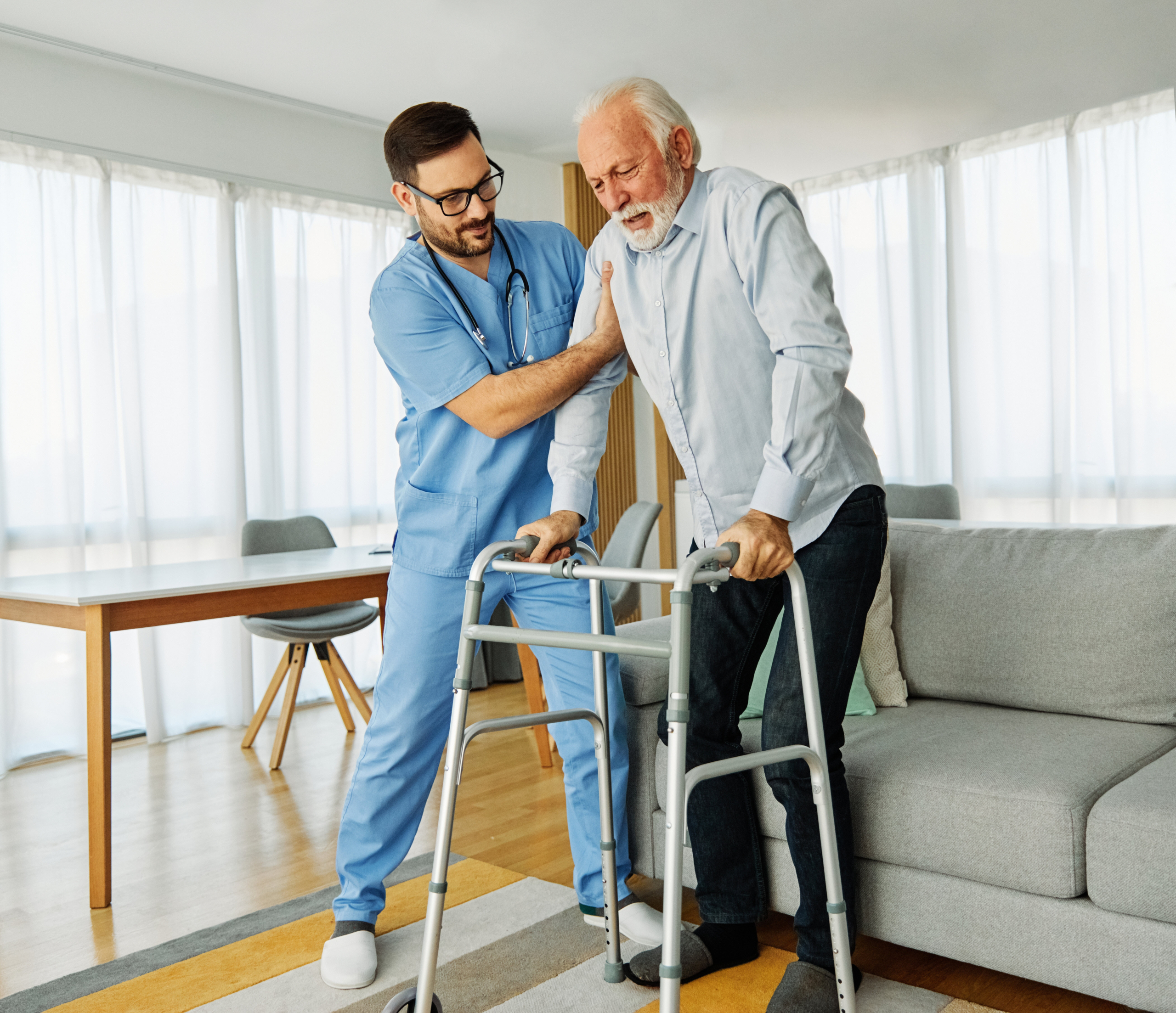 Caregiver helping elderly man with mobility at home