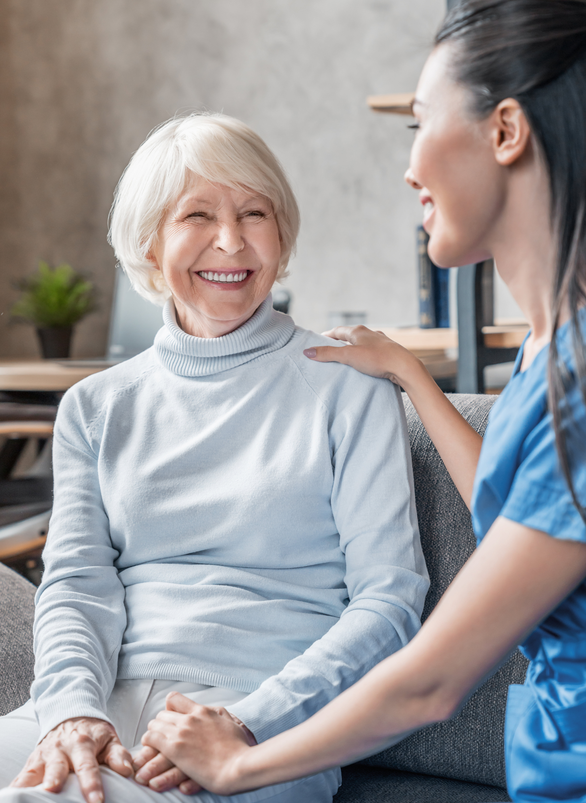 At-Home Caregiver Sitting on Couch with Smiling Senior