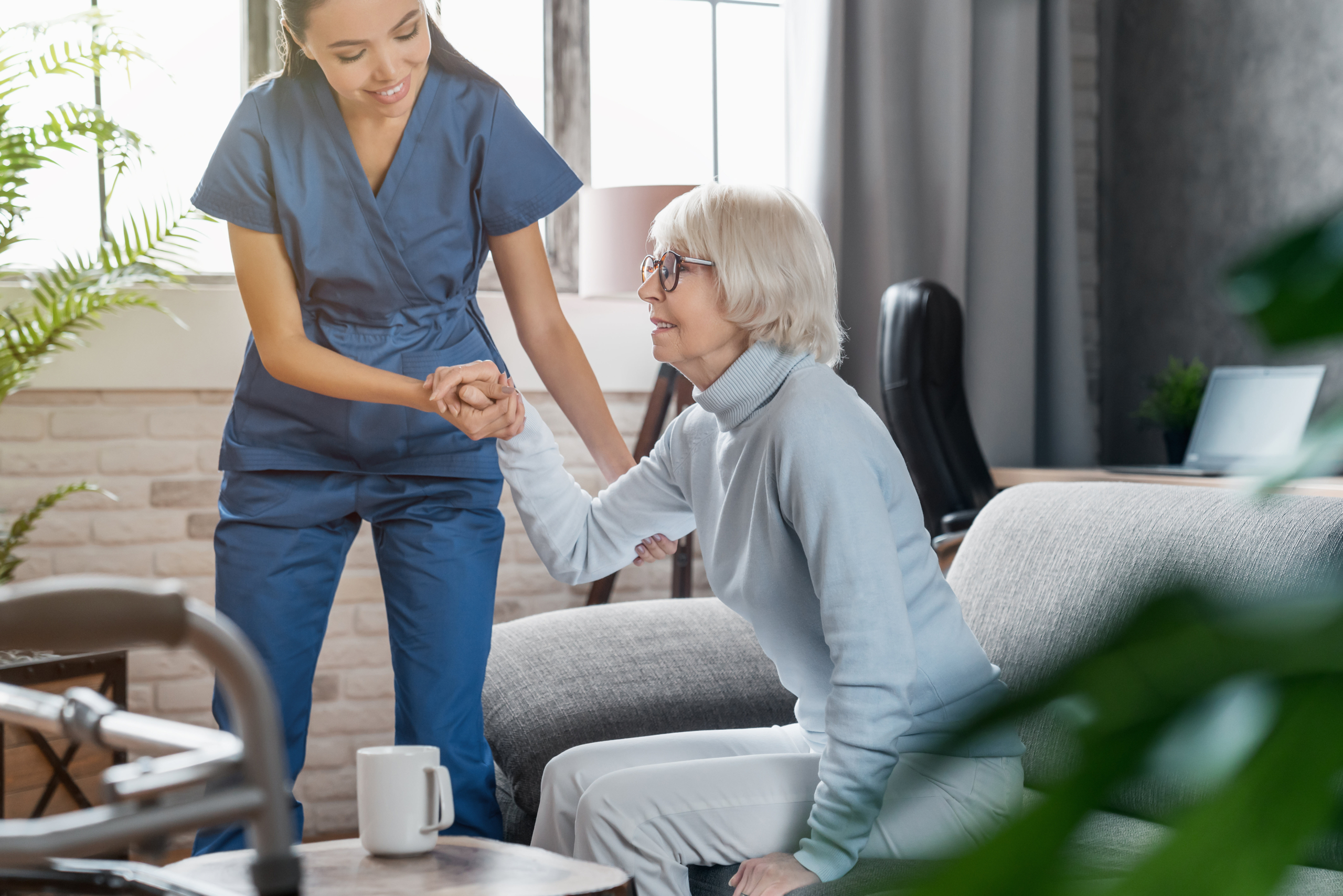 Caregiver helping elderly woman stand up.